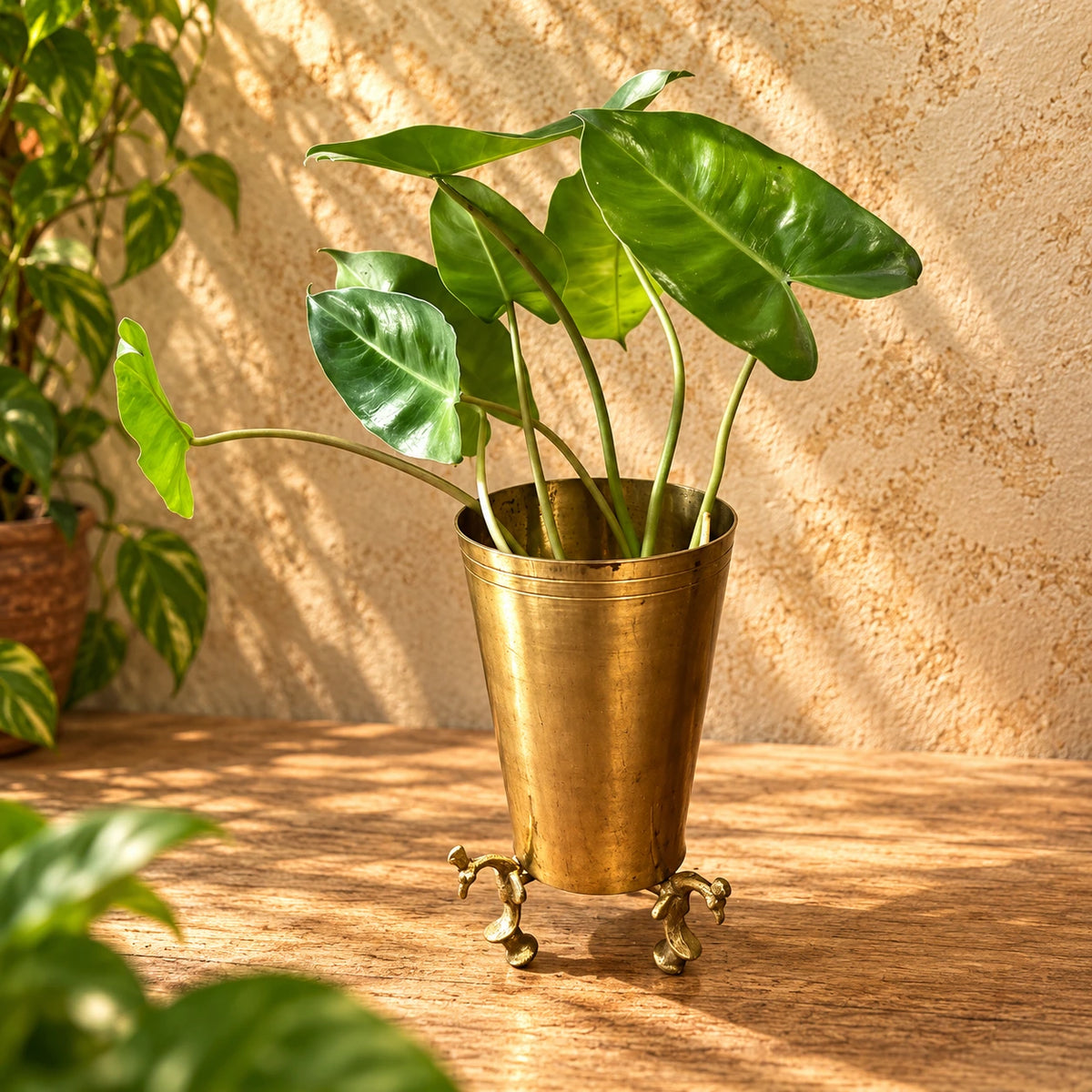 Antique brass glass planter with decorative peacock legs and green indoor plant