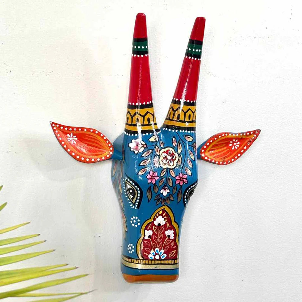 Decorative wall art of a blue deer head with red antlers on a white background