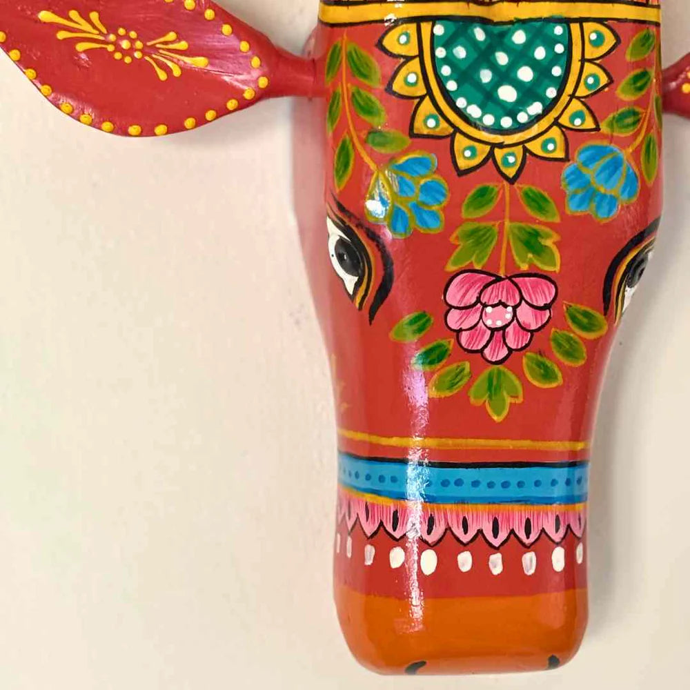Decorative wall art of a colorful cow head with intricate patterns on a beige background