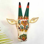 Decorative wall art of a painted animal head with green horns on a white background