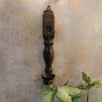 Decorative wall sconce with a textured wall and plant in the foreground