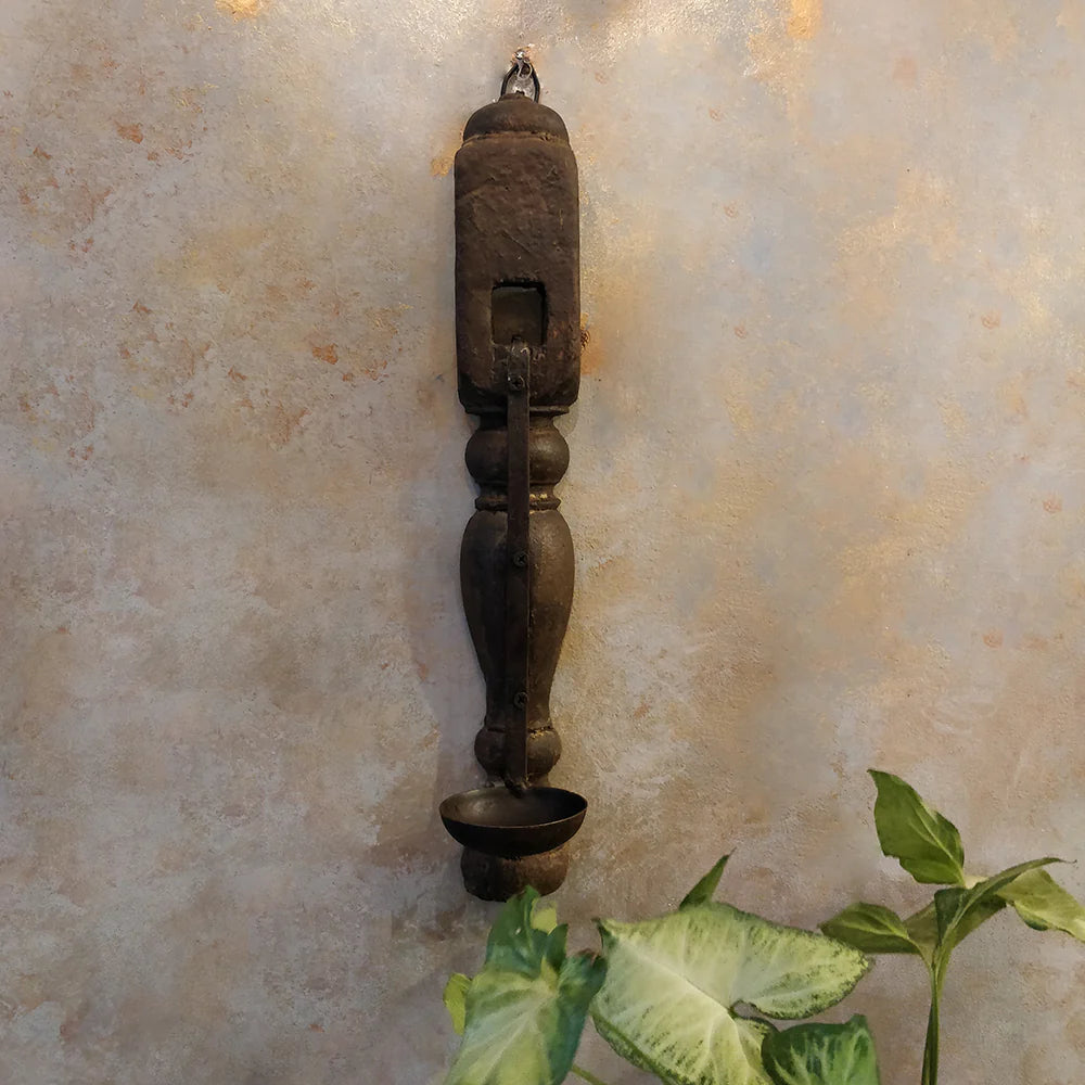 Decorative wall sconce with a textured wall and plant in the foreground
