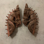 Two ornate wooden horse head sculptures on a textured gray background