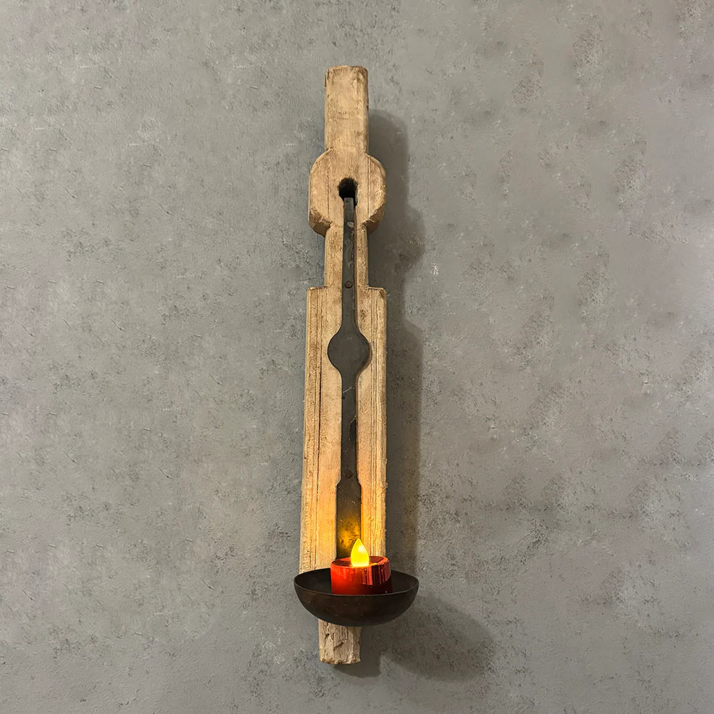 Wooden wall sconce with a candle on a gray concrete wall