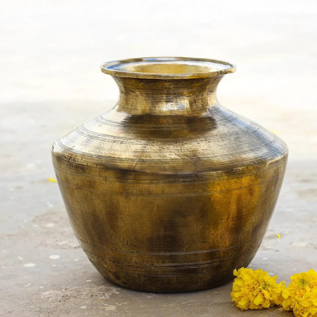Brass pot on a concrete surface with yellow flowers