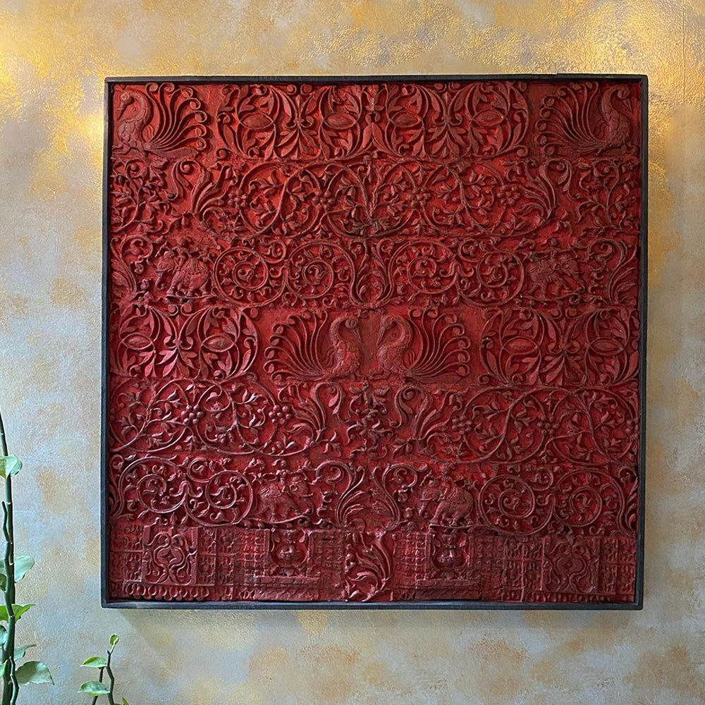 Decorative red textured panel with embossed patterns on a beige wall.