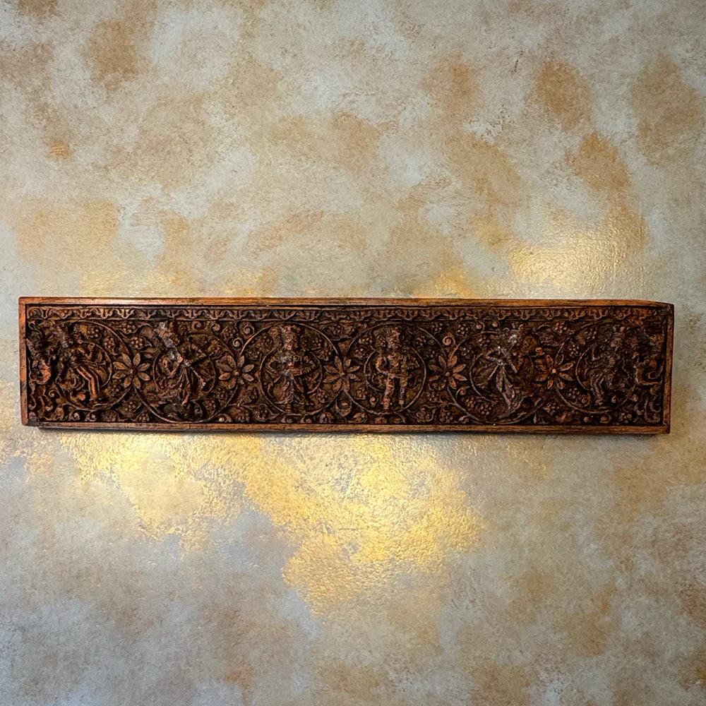 Decorative metal wall art with intricate designs on a textured beige wall.