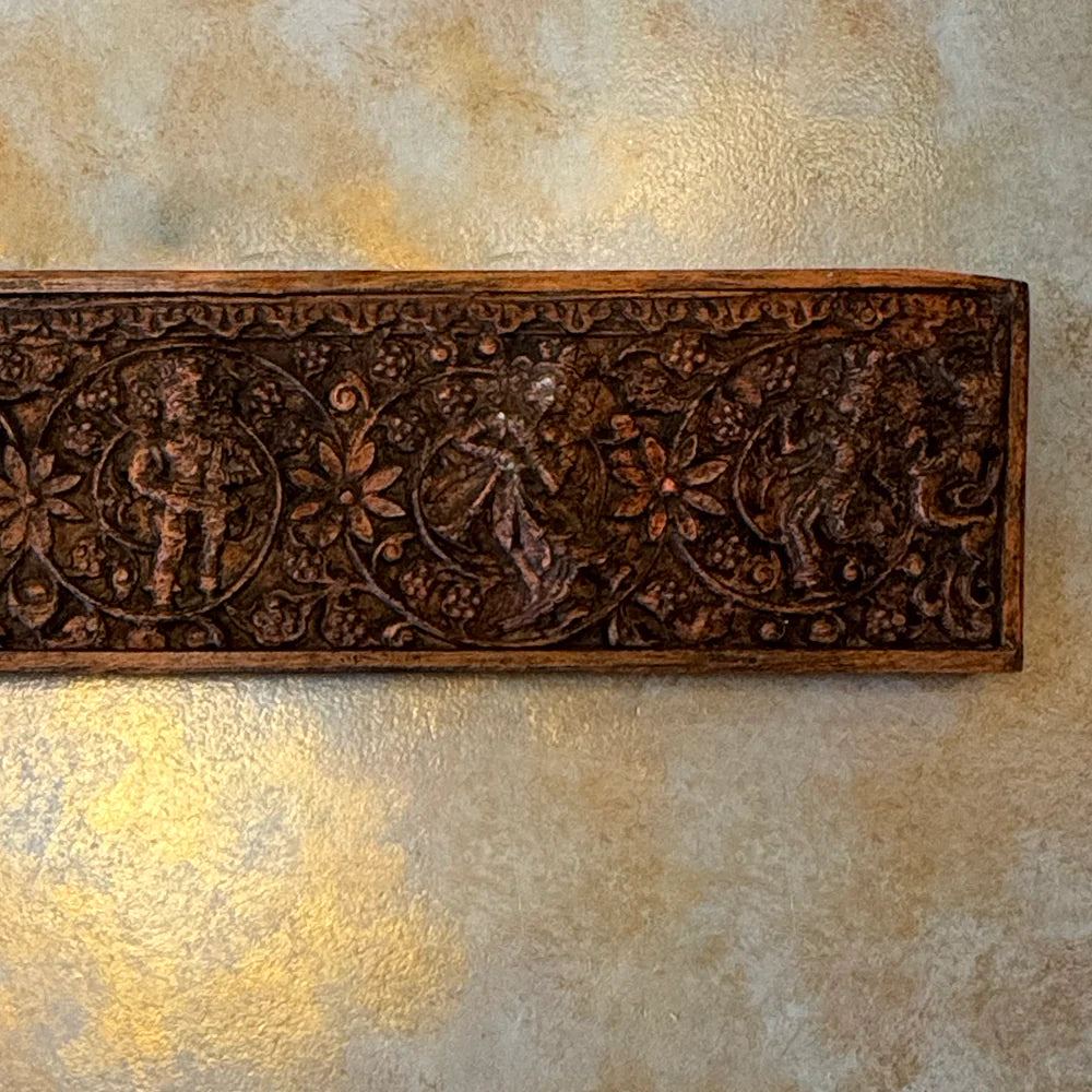 Decorative wooden panel with intricate carvings on a textured wall.