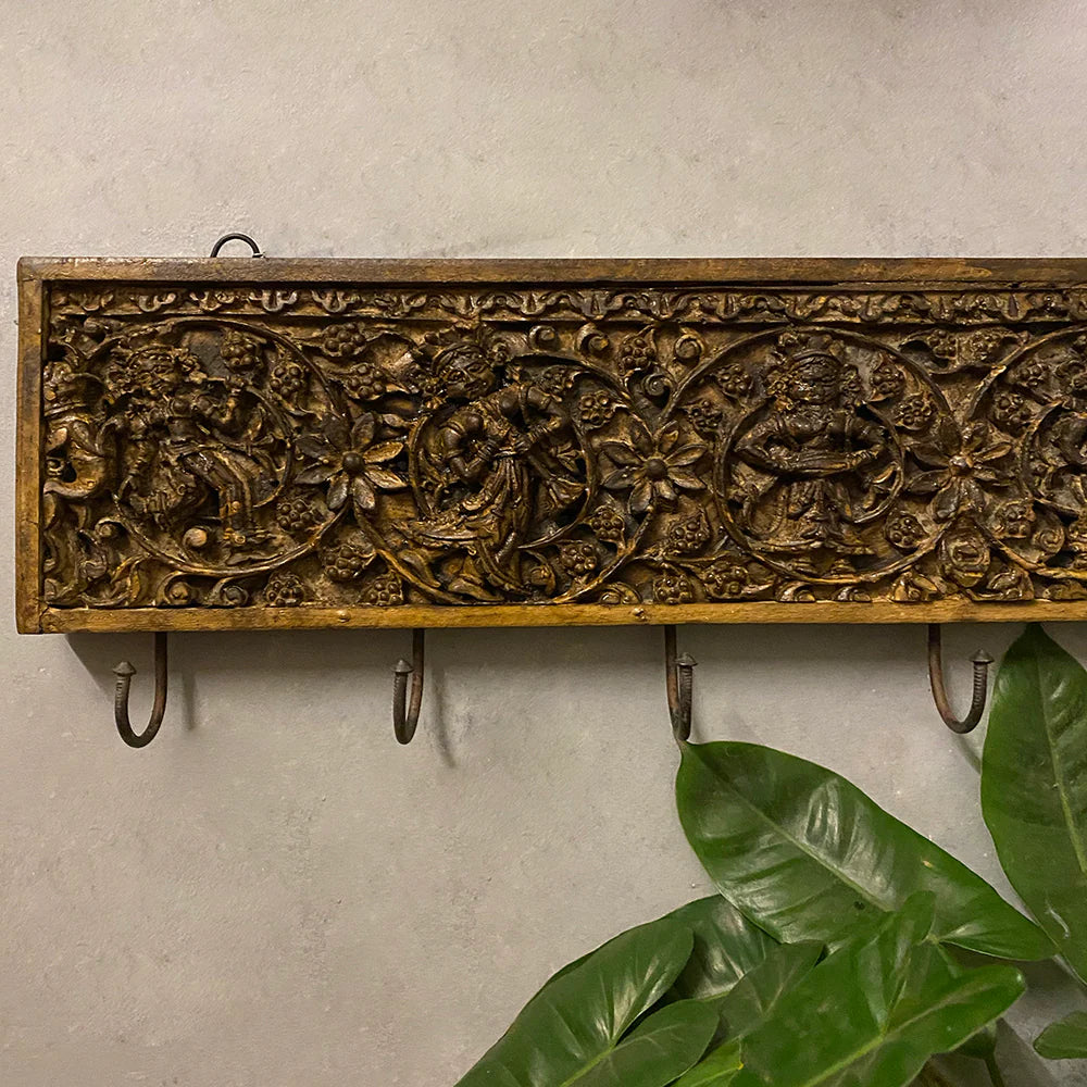 Decorative wall panel with carvings and hooks on a light background