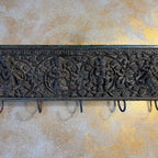Decorative metal wall hook with intricate designs on a textured wall.