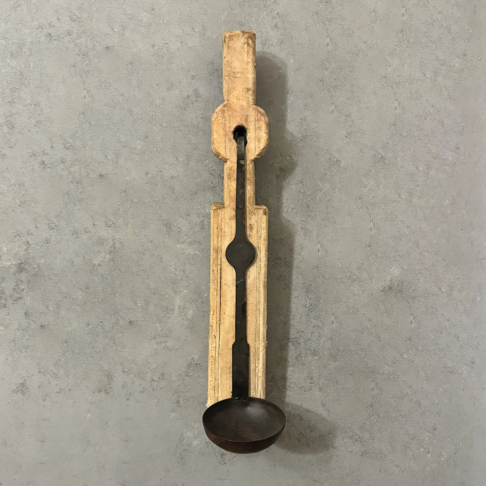 Wooden ladle with black spoon on a gray concrete background