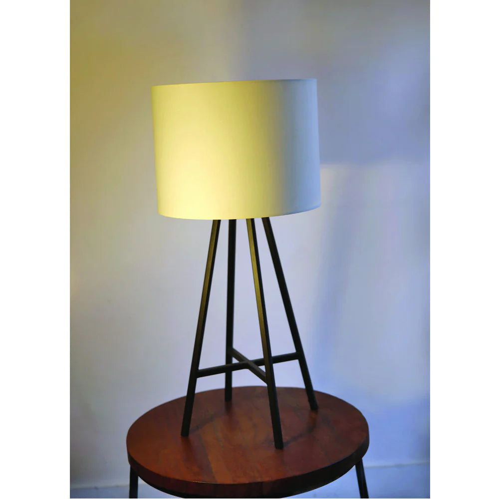 Table lamp with a yellow shade on a wooden base against a plain wall.
