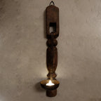 Rustic metal wall sconce with a candle on a textured wall