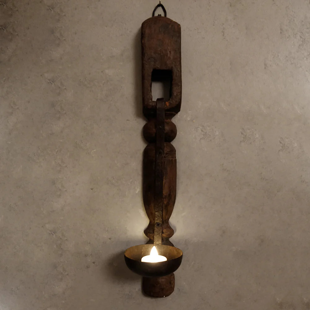 Rustic metal wall sconce with a candle on a textured wall