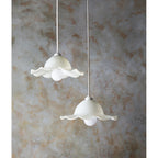 Two white floral pendant lights against a textured wall.