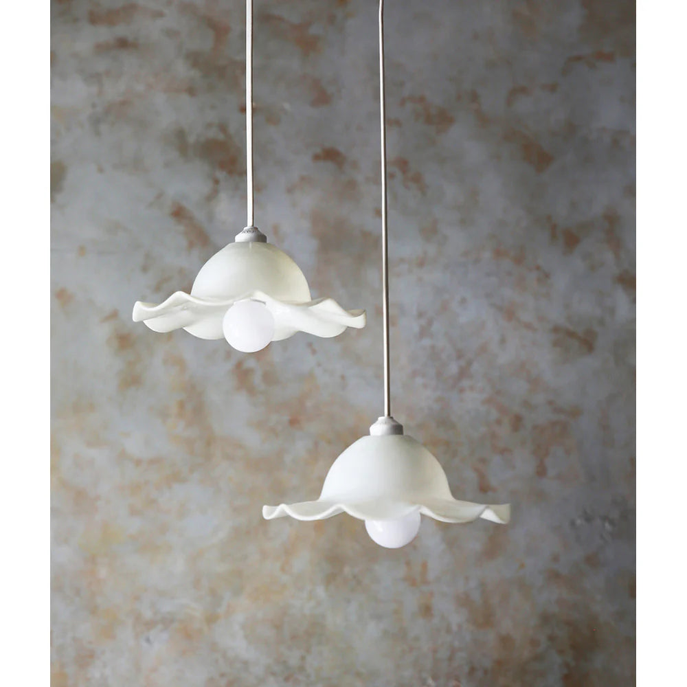 Two white floral pendant lights against a textured wall.