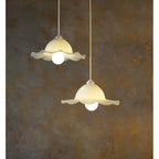 Two floral pendant lights hanging against a textured brown wall.