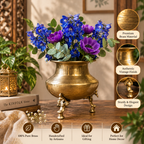 A brass three-legged flower pot filled with blue and purple flowers, styled on a wooden table with decorative plants and a lantern. Callout circles on the right highlight premium brass material, vintage finish, and elegant design, with feature icons along the bottom.