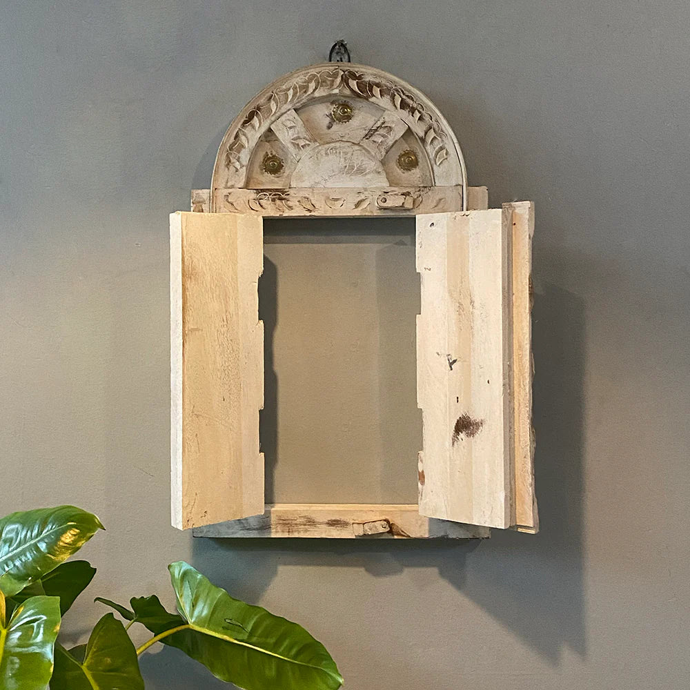 Decorative wooden mirror with intricate carvings on a gray wall