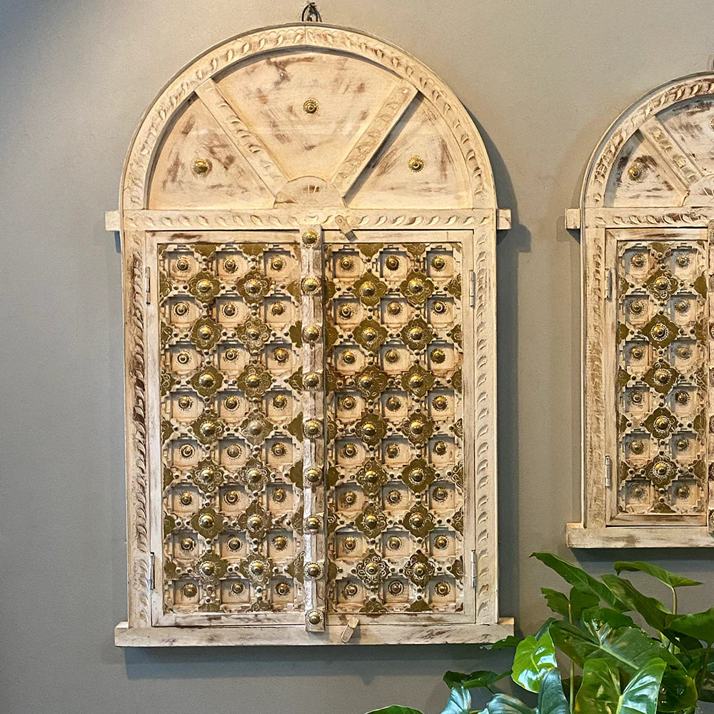 Decorative wall art resembling a vintage door with intricate patterns on a gray wall.