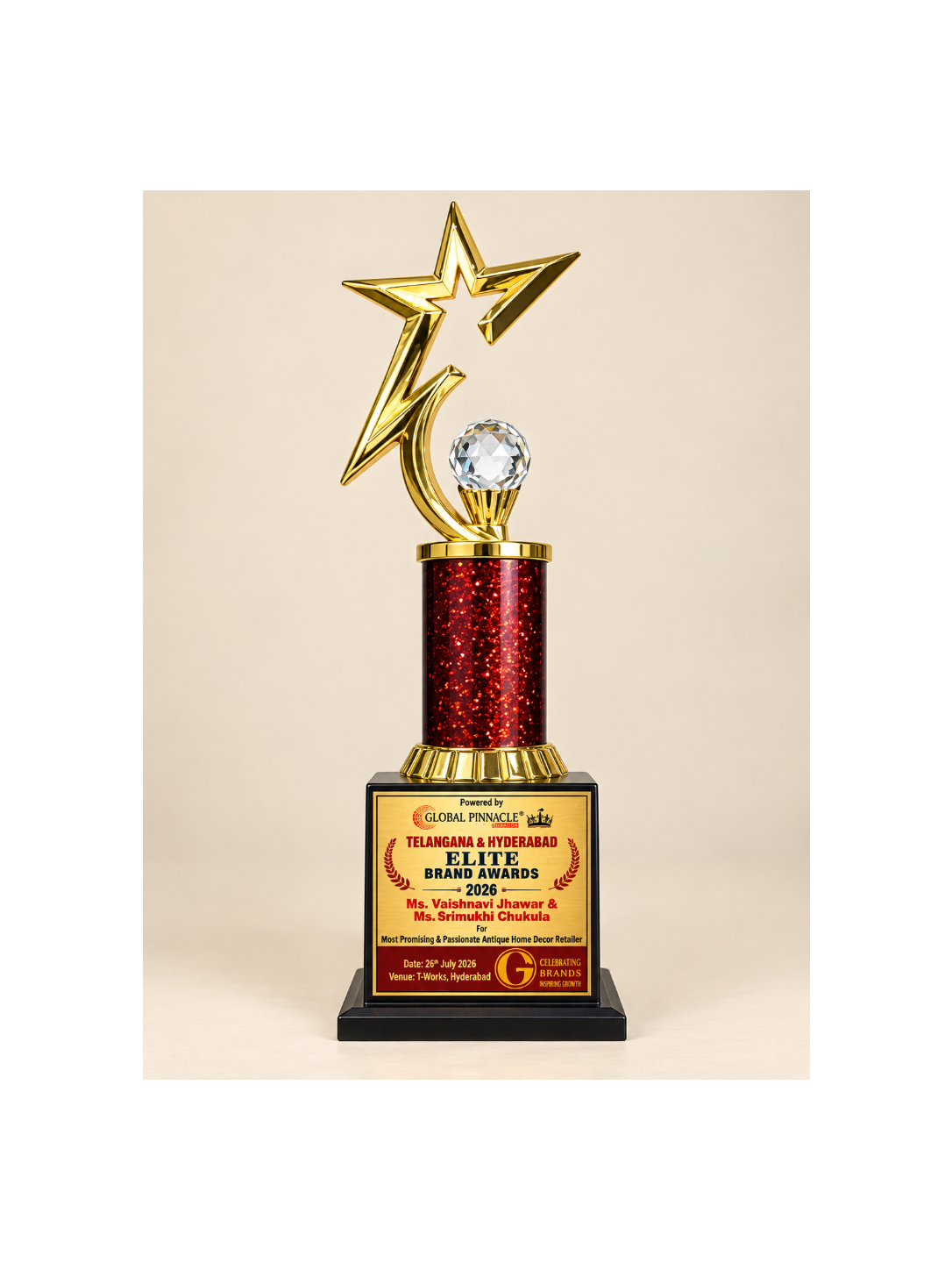 A large trophy award with a gold star and crystal ball on a red glitter column, mounted on a black base with a gold and red plaque, photographed against a light beige background.