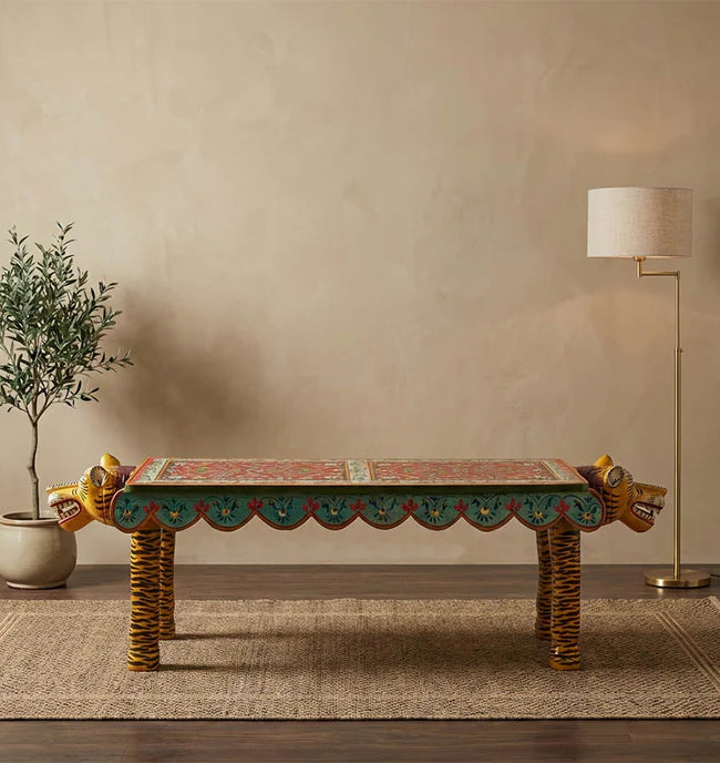 Decorative table with intricate designs in a room with a plant and lamp.